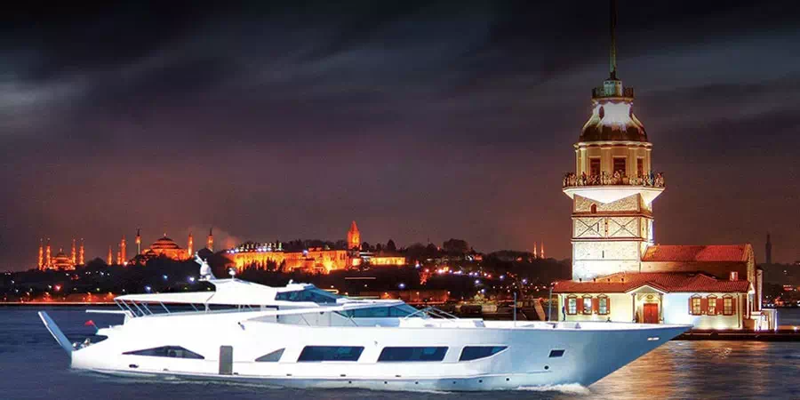 Luxury yacht lit up on the Bosphorus at night by the Maiden's Tower