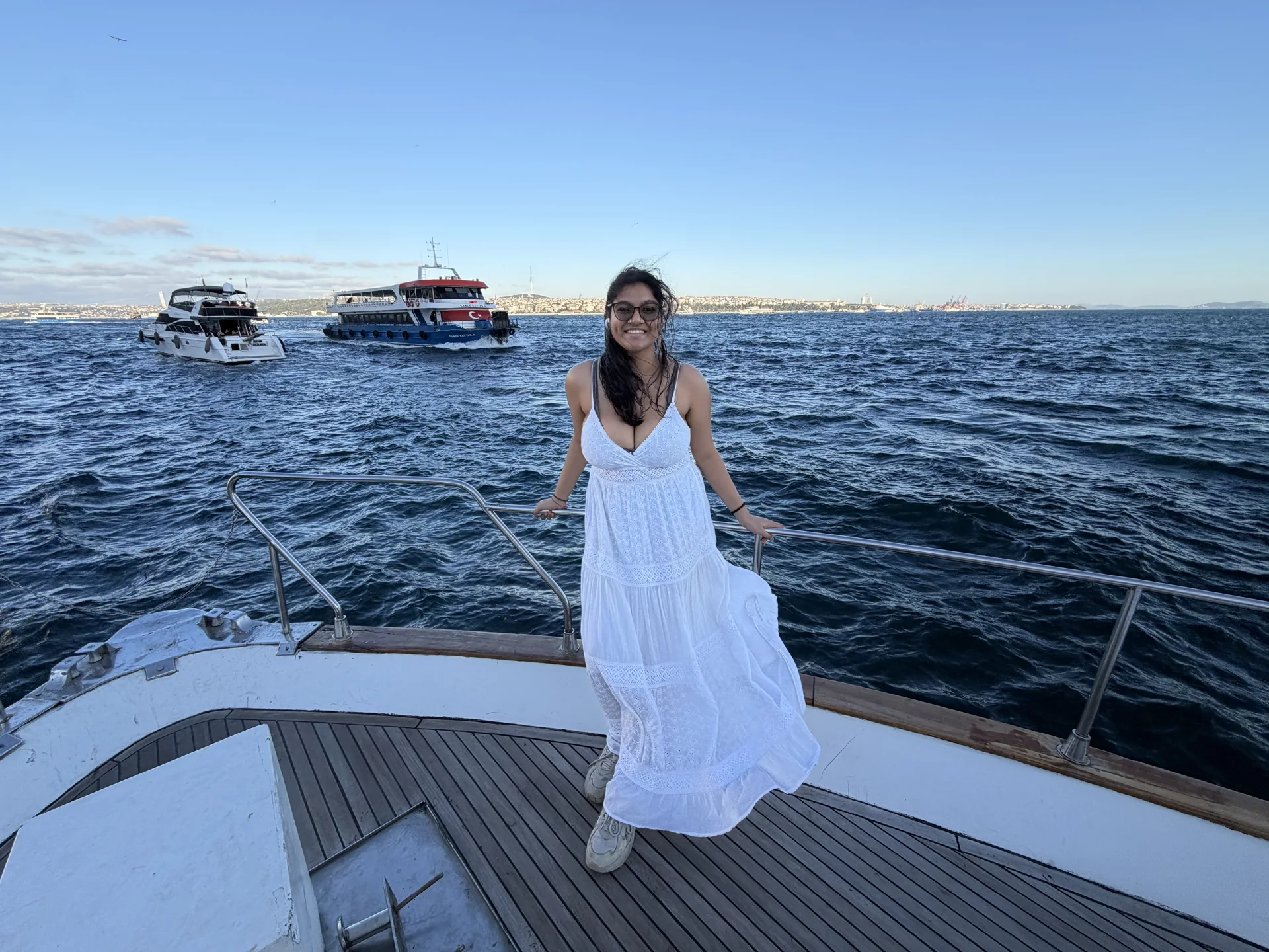 A guest in a white dress on the bow of a private yacht on the Bosphorus